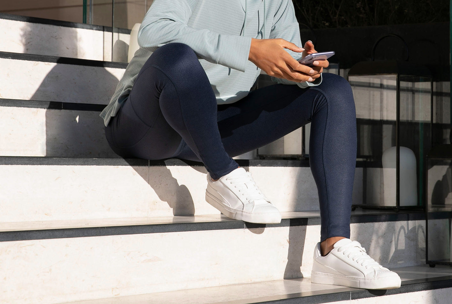 Woman sitting on steps wearing Mondetta dark blue leggings