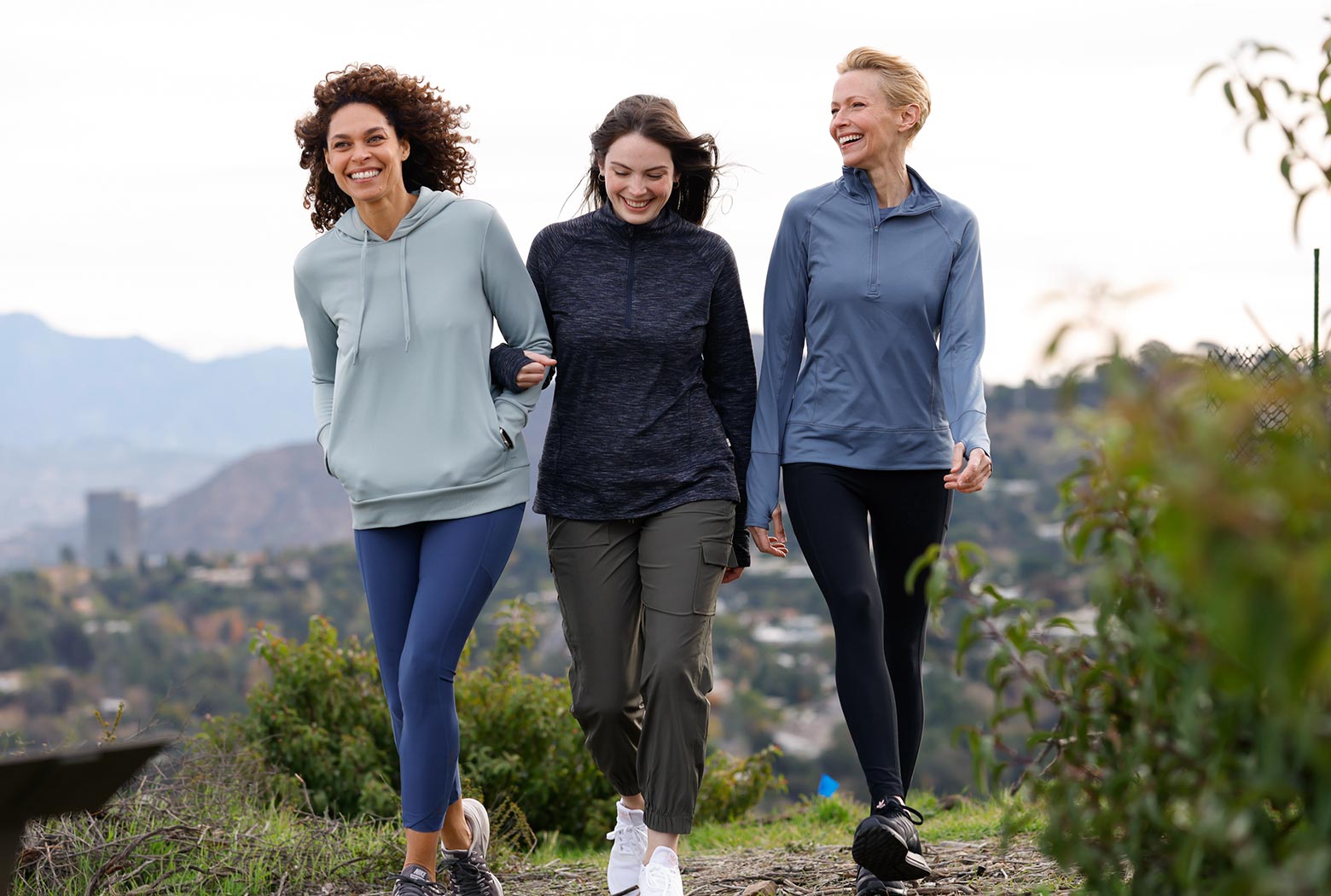 Three female Mondetta models climbing a hill wearing various coverup tops