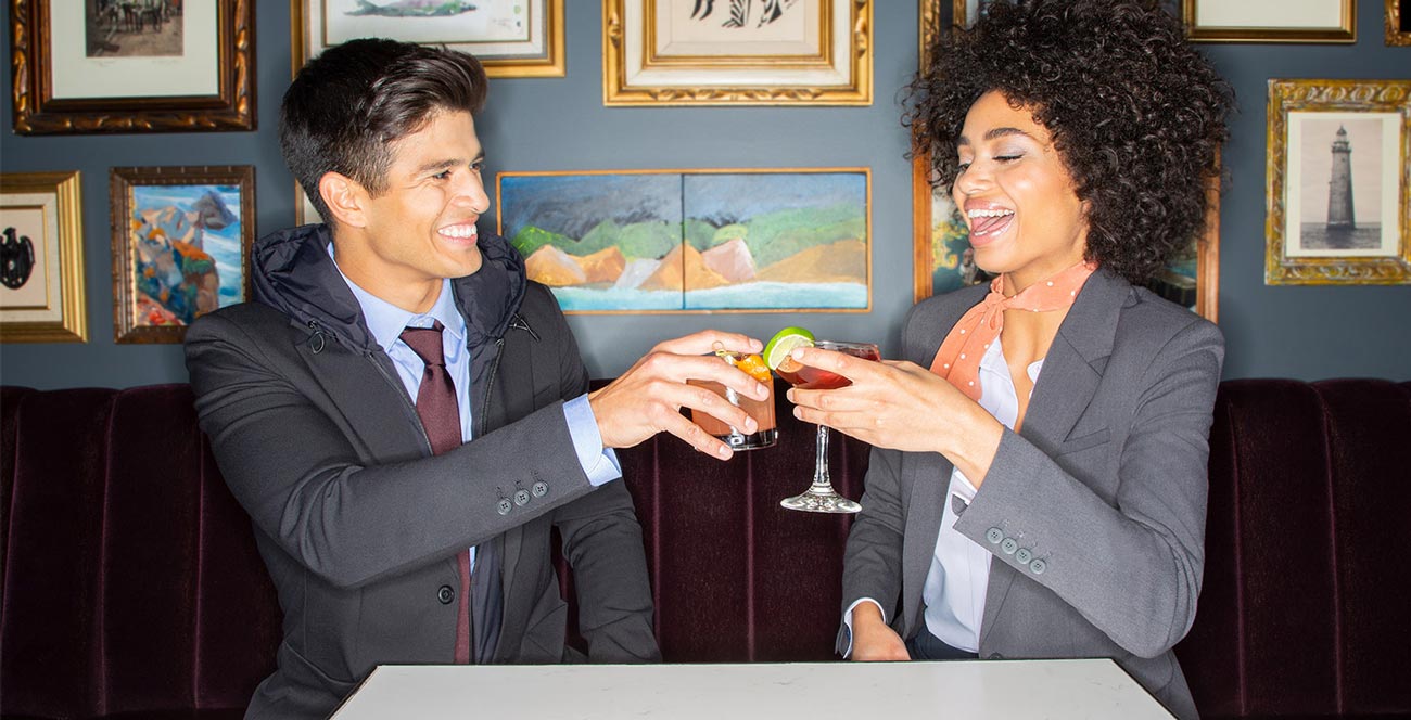 Man and woman having a cocktail wearing Modern Ambition suits